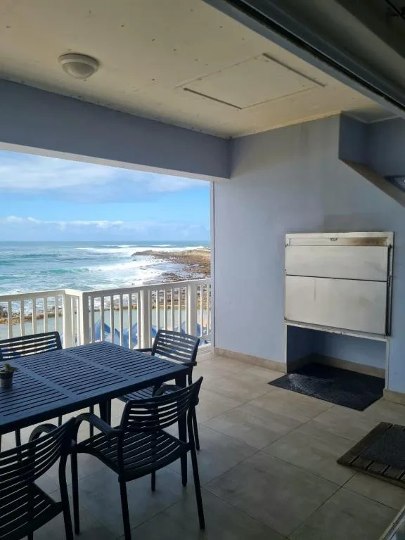 Beachfront deck with dining table overlooking ocean and coastline