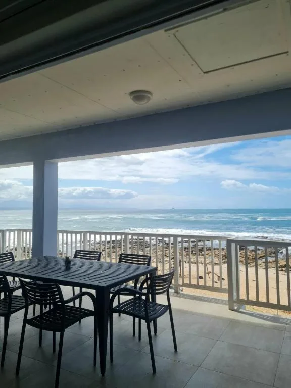 Covered oceanfront balcony with dining table overlooking pristine beach and sea