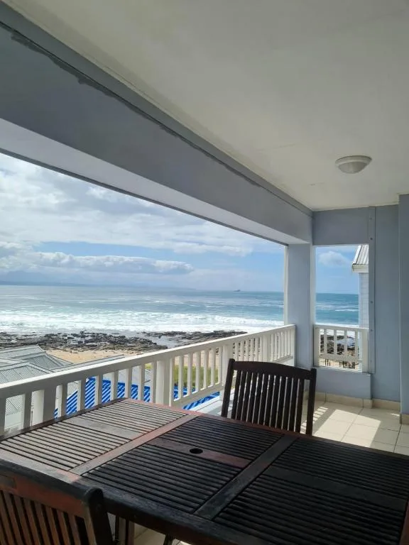 Oceanfront covered deck with seating overlooking Mossel Bay beach and waves