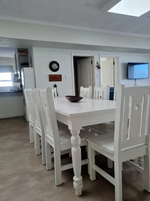 White dining table with chairs in bright open-plan accommodation