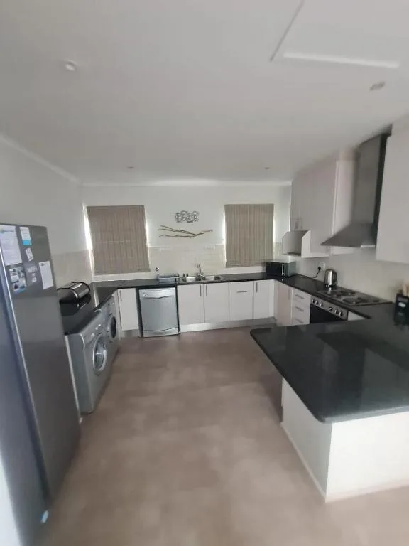 Modern kitchen with white cabinetry, black countertops, stainless steel appliances