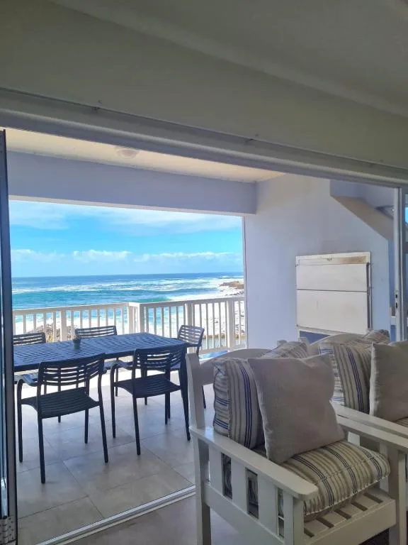 Bright lounge with ocean view through sliding glass doors and deck beyond