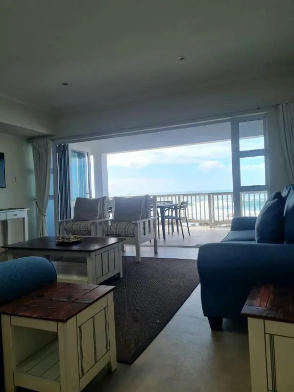 Spacious lounge with blue seating and panoramic ocean views through glass doors