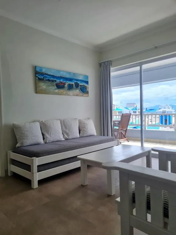 Bright lounge with sofa, coffee table, and ocean view through glass doors