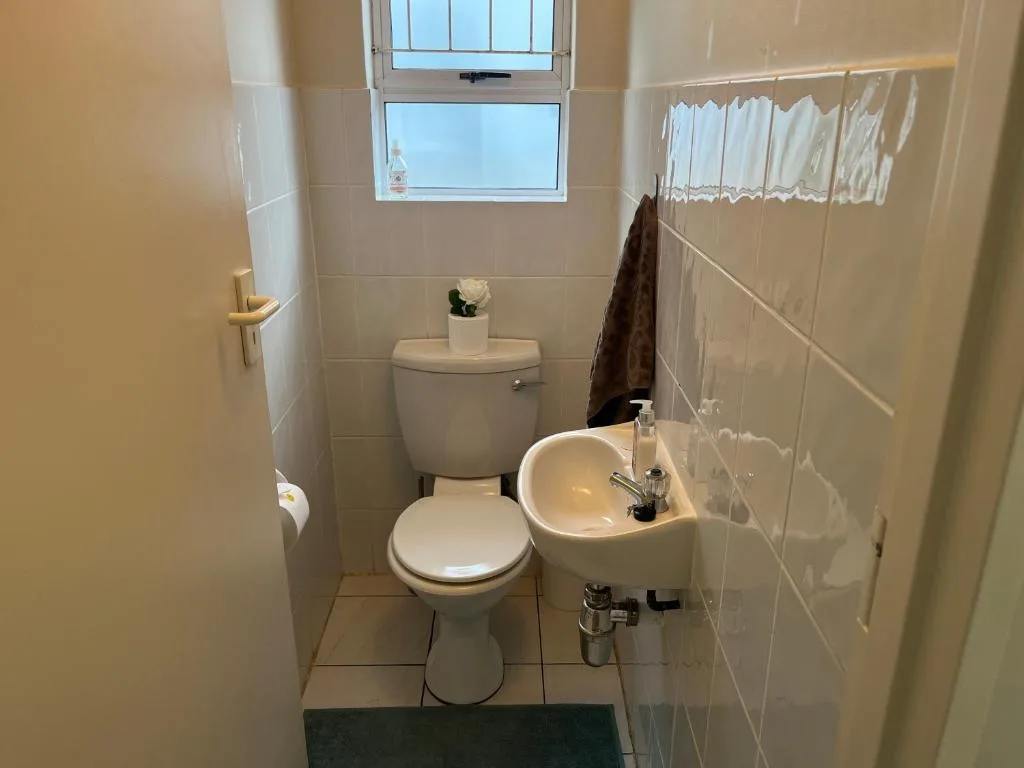 Clean bathroom with toilet, sink, and window with natural light