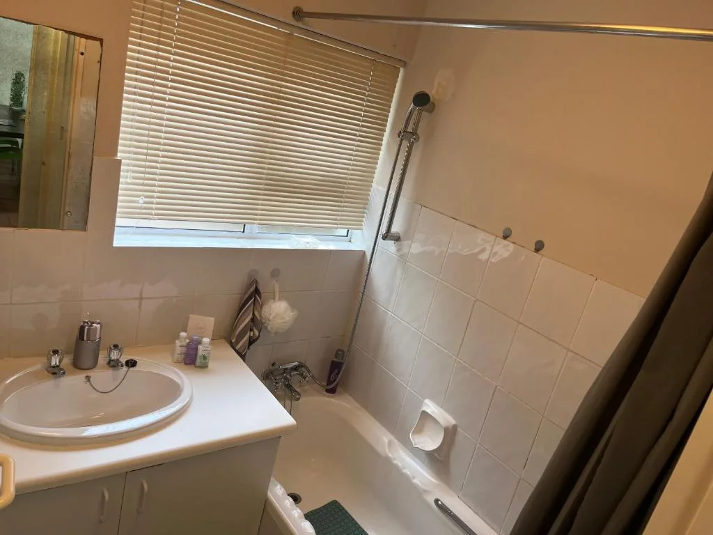 Bright bathroom with round sink, tiled shower enclosure, window blinds