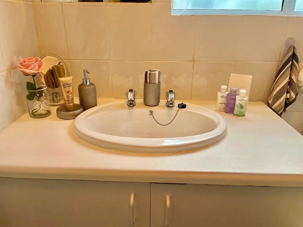 Modern bathroom vanity with round sink, decorative accessories, and toiletries