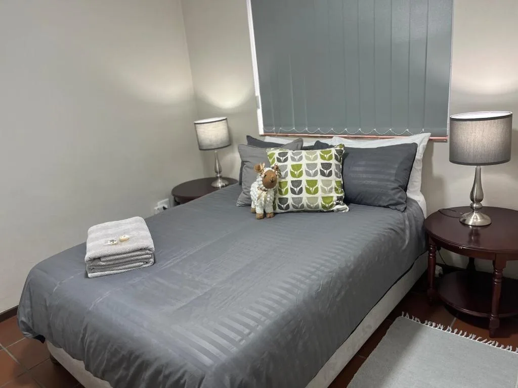 Spacious bedroom with gray bed, decorative pillows, and bedside lamps