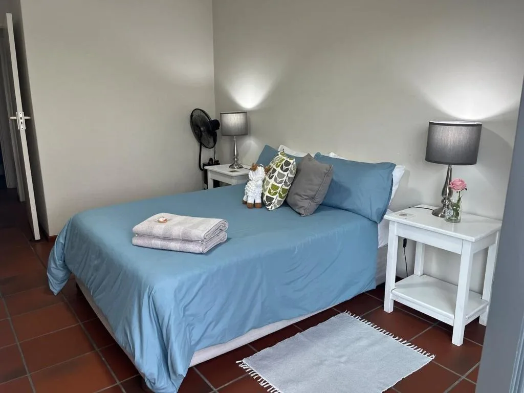 Neatly made bed with blue linens and bedside tables with lamps