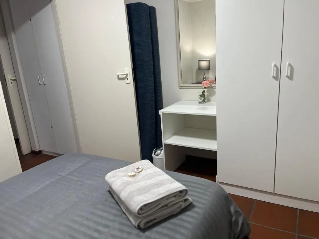 Bedroom with bed, vanity mirror, wardrobe storage, and fresh white towels