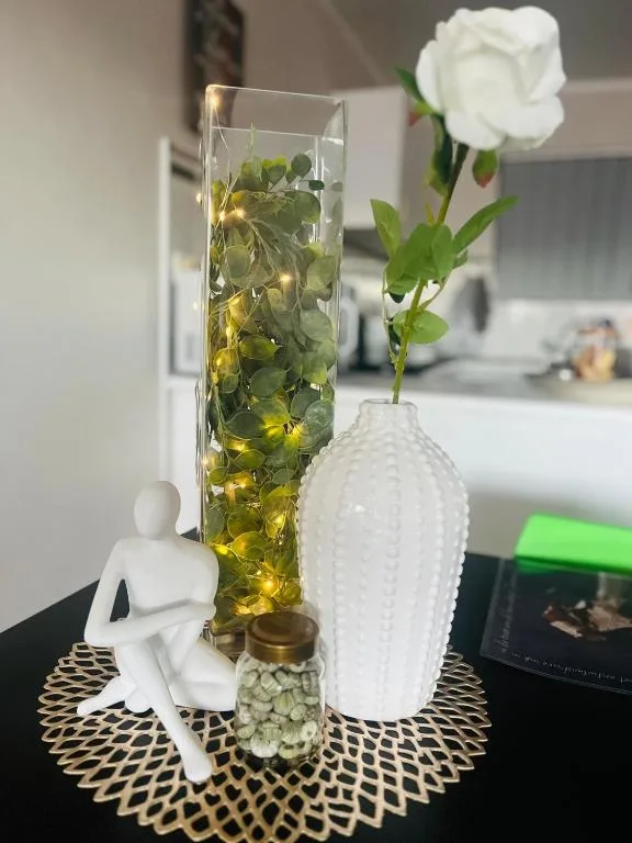 Decorative vases and flowers on table with white figurine