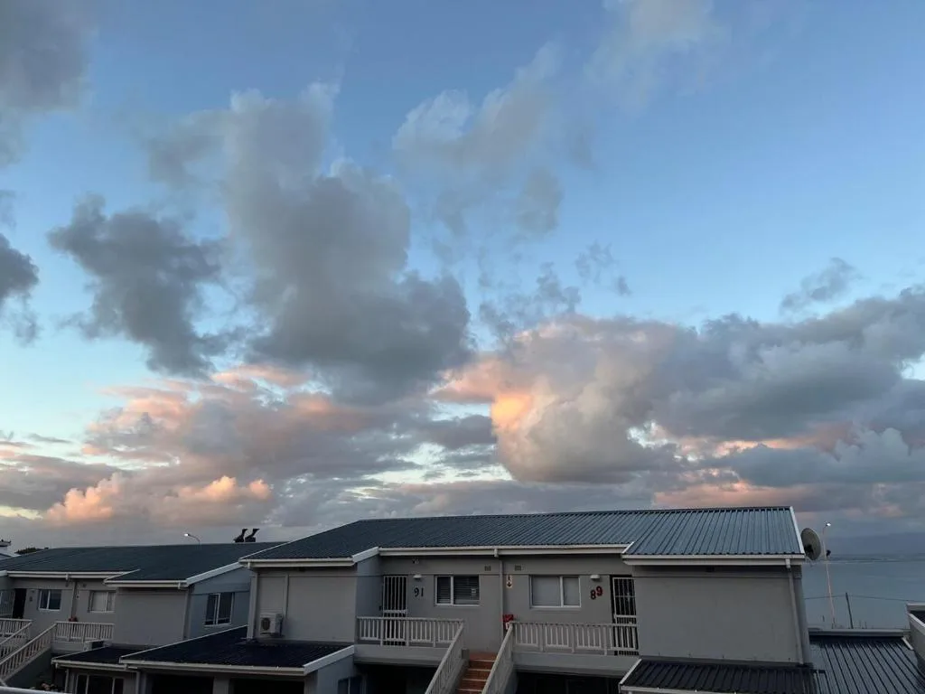 Waterfront apartment building with metal roof and dramatic sunset clouds