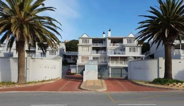 White multi-story apartment building with palm trees and gated entrance