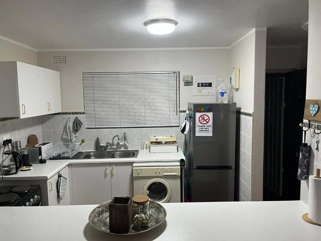 Compact kitchen with white cabinetry, black appliances, and tiled splashback