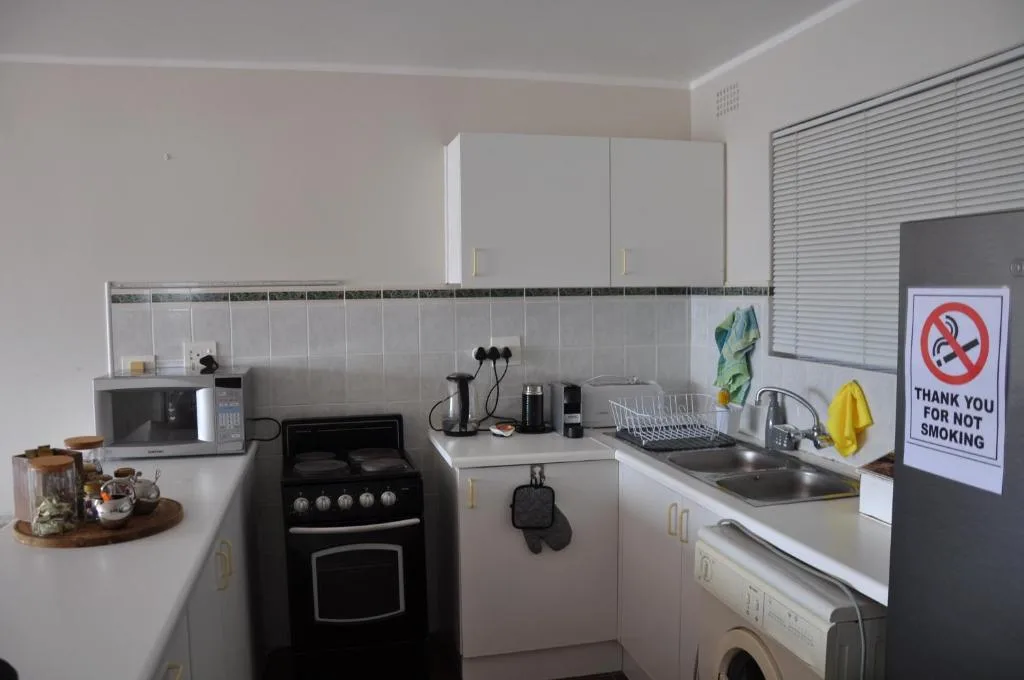 Compact kitchen with black electric stove, sink, and white cabinetry