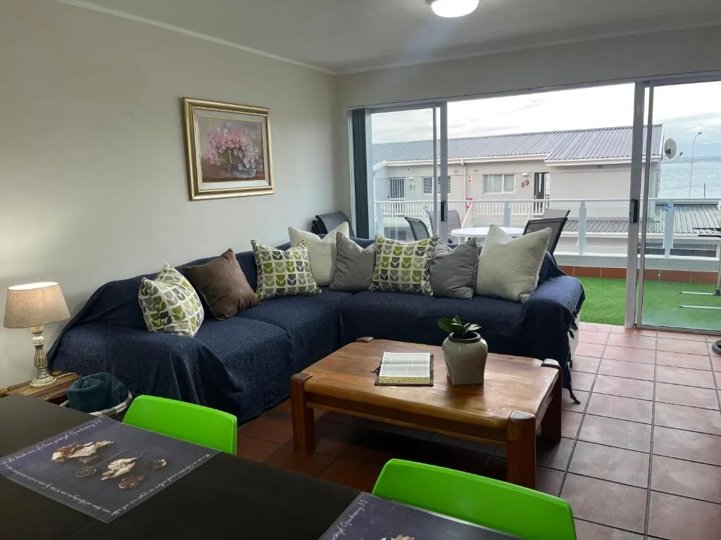 Spacious lounge with navy corner sofa, wooden coffee table, and sliding doors to deck