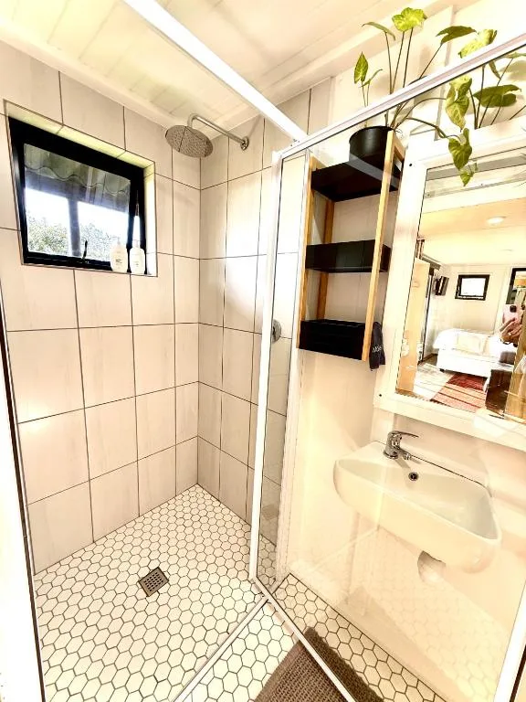 Spacious bathroom with walk-in shower, vanity sink, and fresh flowers