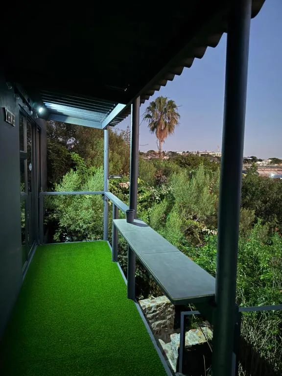 Modern deck with green artificial turf, covered pergola, and panoramic landscape views
