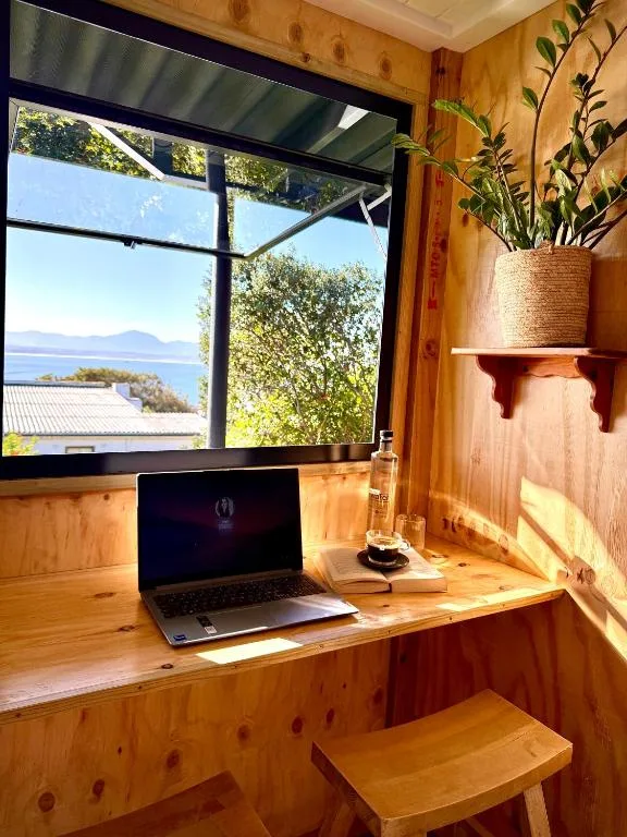 Wooden desk with laptop overlooking scenic coastal mountain views through large window