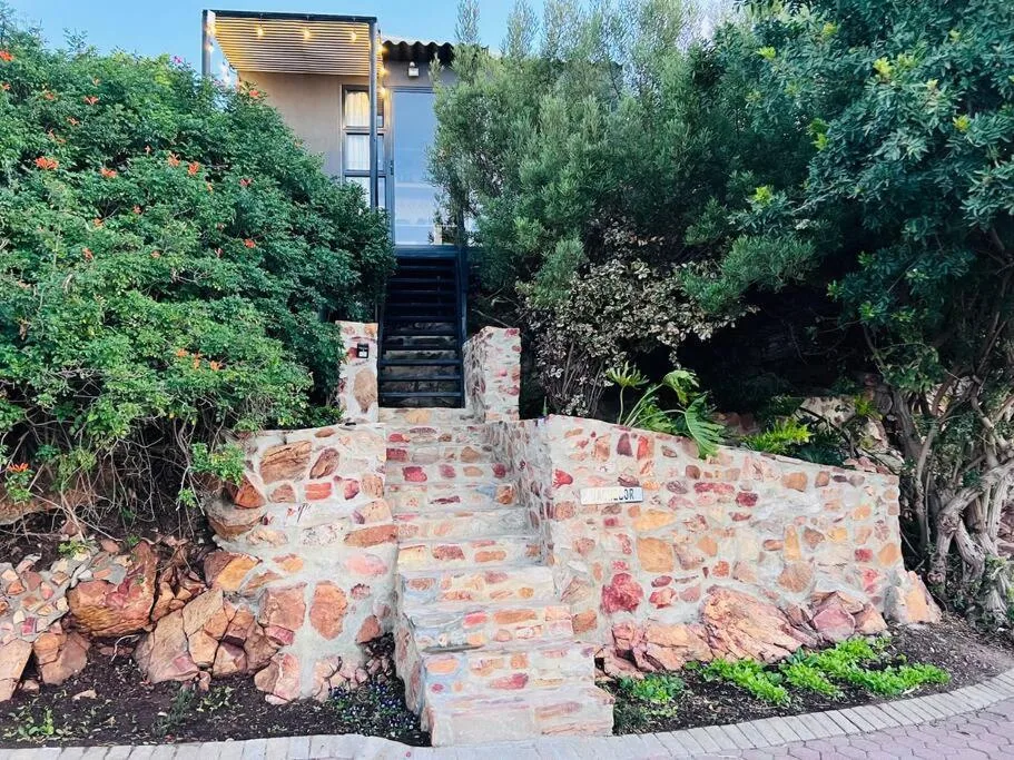 Stone entrance stairs leading to modern apartment with lush green vegetation