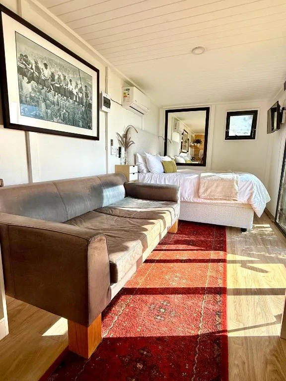 Spacious lounge with leather sofa, bed, and framed artwork on walls