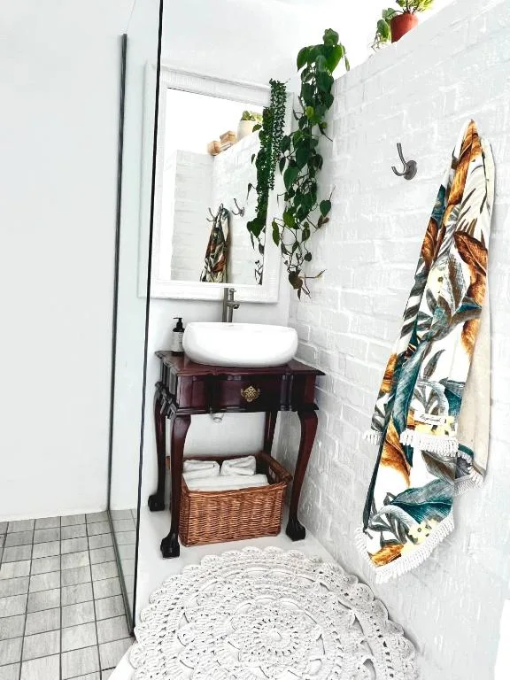 Compact bathroom with round sink, mirror, and decorative plants and towels