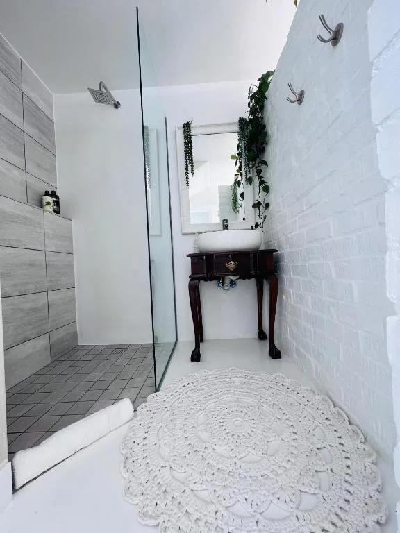 Modern bathroom with walk-in shower, vanity sink, and white tile walls