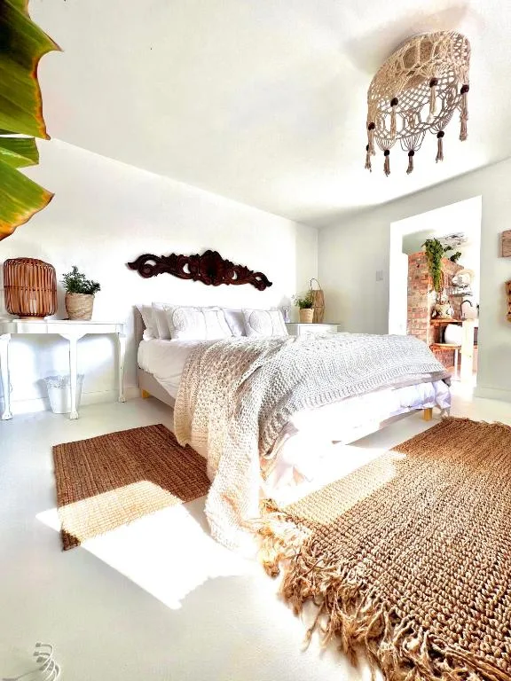 Bright bedroom with white bed, woven pendant light, and natural decor accents