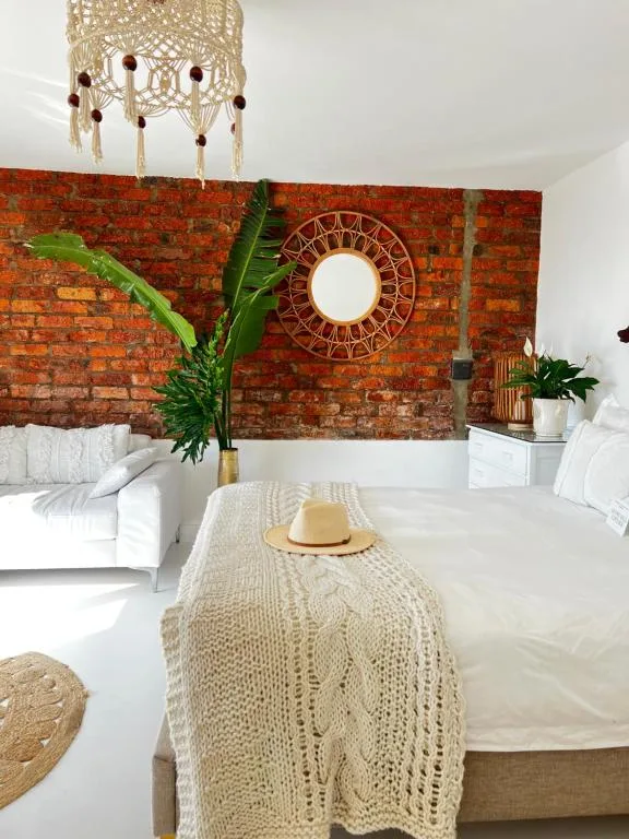 Bright bedroom with exposed brick wall, double beds, and boho decor