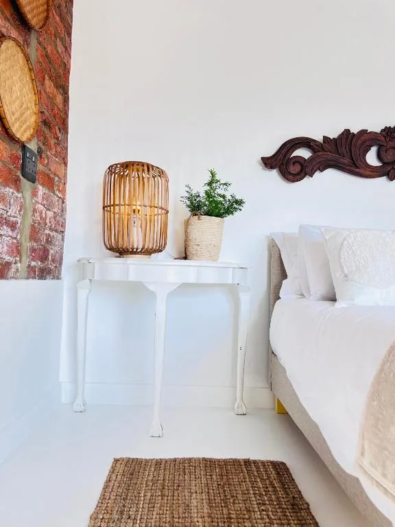 Bright bedroom corner with white bed, wooden decor accents, potted plant