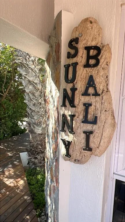 Wooden sign reading Sunny Bali mounted on cottage exterior wall