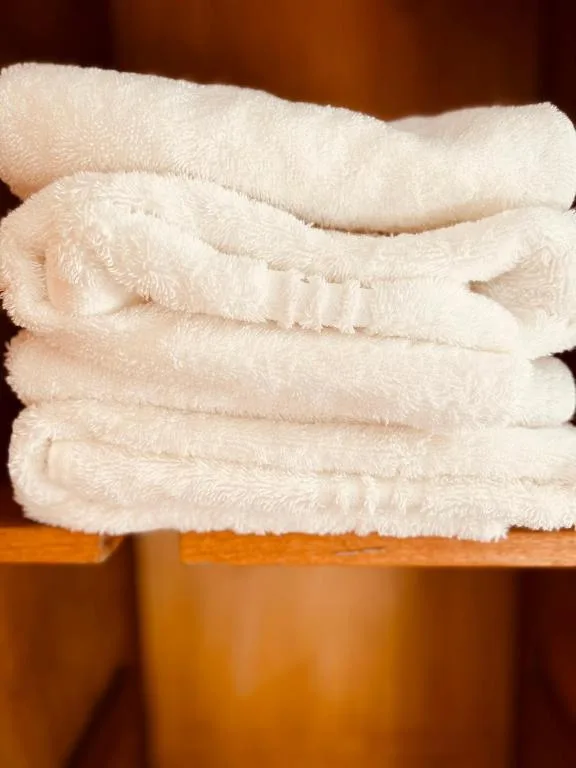 Soft folded white towels stacked on wooden shelf
