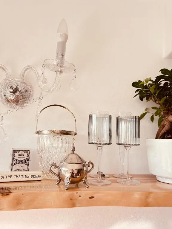 Decorative glassware, crystal vessels, and vintage ornaments on wooden shelf