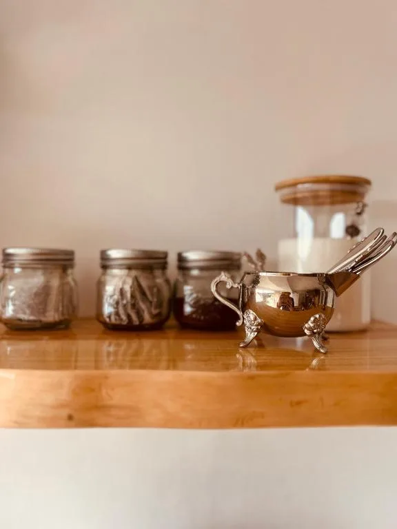 Decorative kitchen shelf with vintage jars, gravy boat, and wooden counter