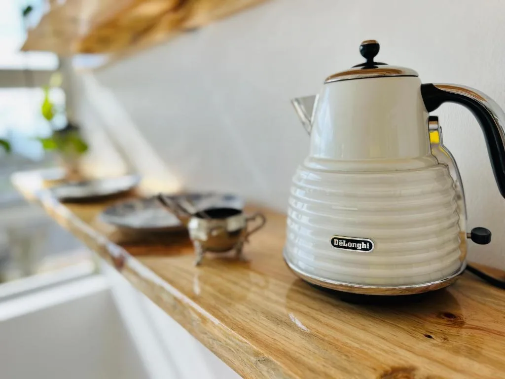 White DeLonghi electric kettle on wooden kitchen counter