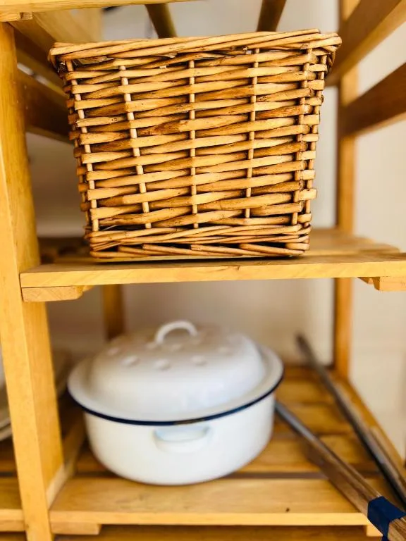 Woven storage basket and enamel pot on wooden shelving unit