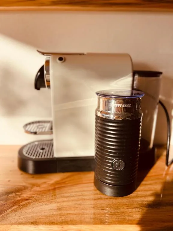 Espresso machine and milk frother on wooden counter with warm lighting
