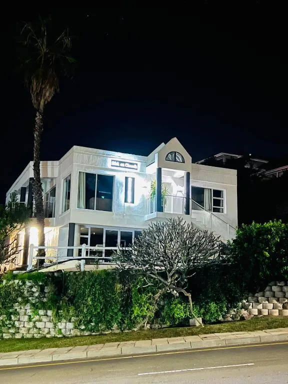 Modern white beachfront cottage illuminated at night with palm trees
