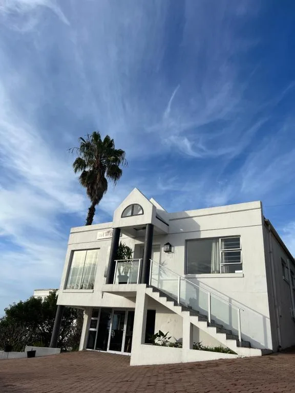 Modern white cottage with palm tree and external staircase against blue sky