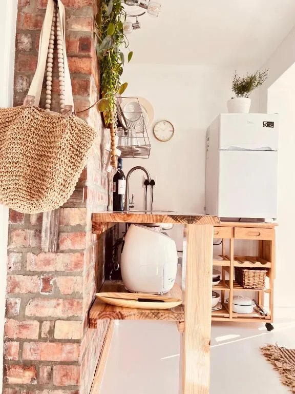 Compact kitchenette with white fridge, wooden counter, and brick accent wall
