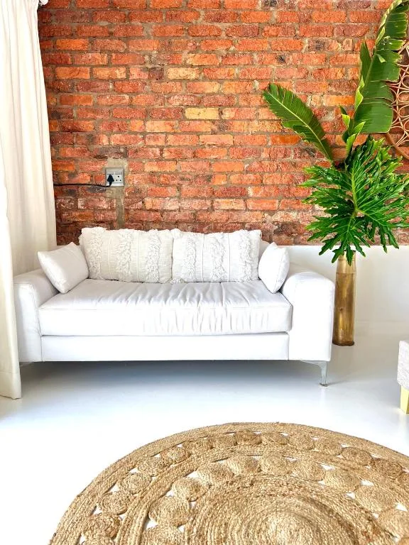 Bright living room with white sofa against exposed brick wall and greenery