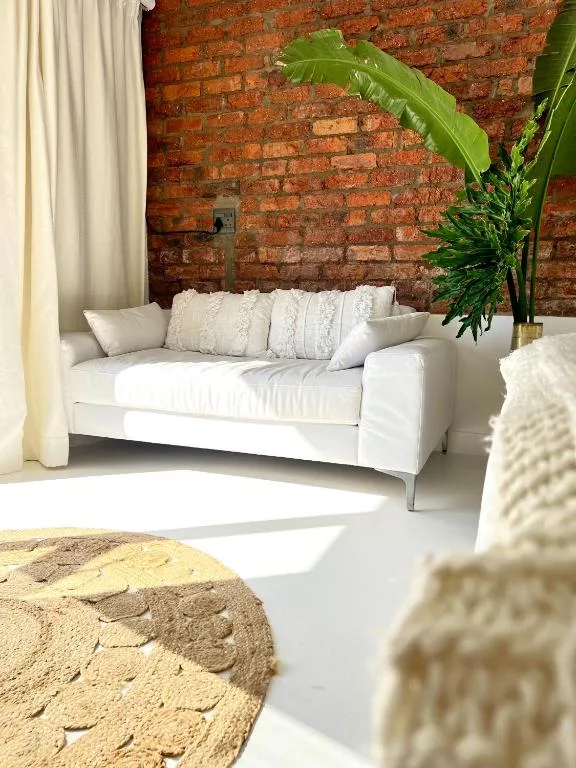 Bright living room with white sofa against exposed brick wall and green plants