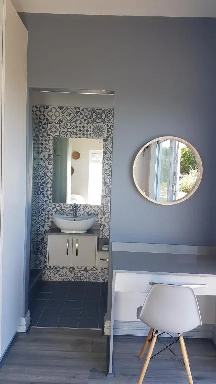 Modern bathroom with patterned tile accent wall and round mirror