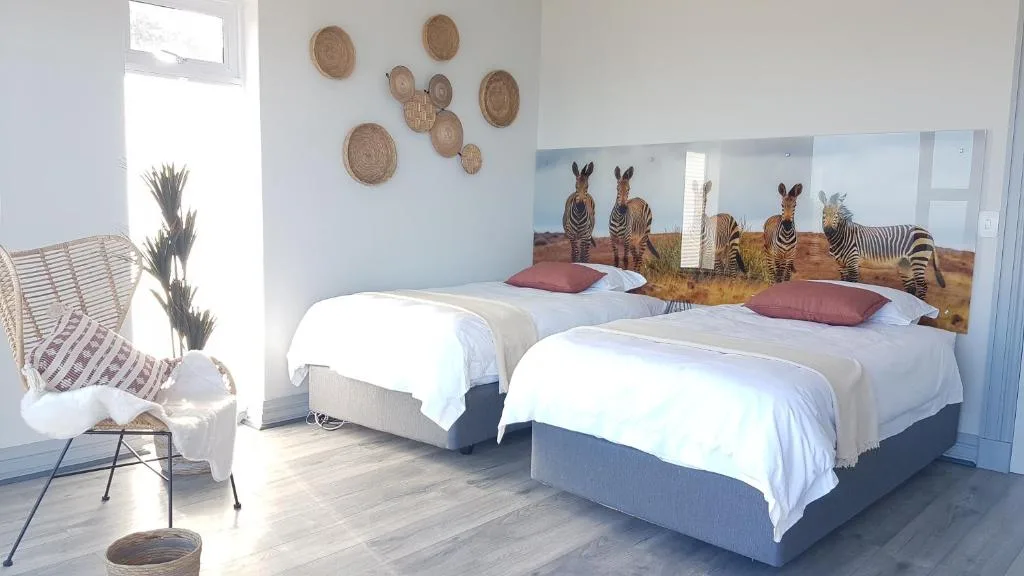 Twin beds with white linens and zebra headboard artwork in bright room