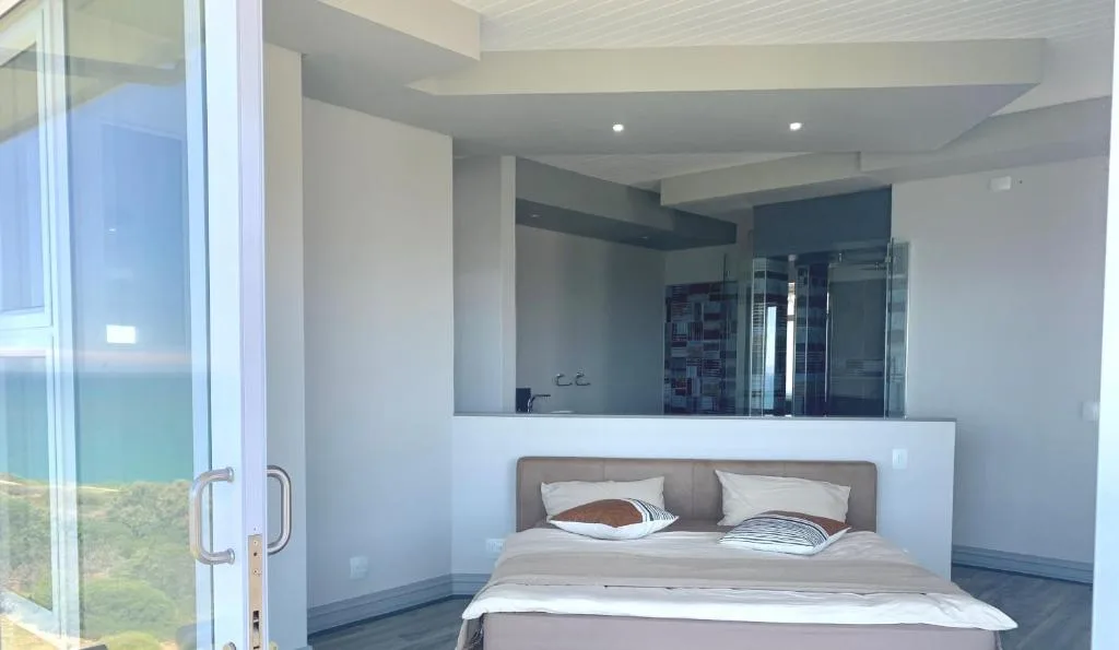 Modern bedroom with en-suite bathroom visible through glass partition wall