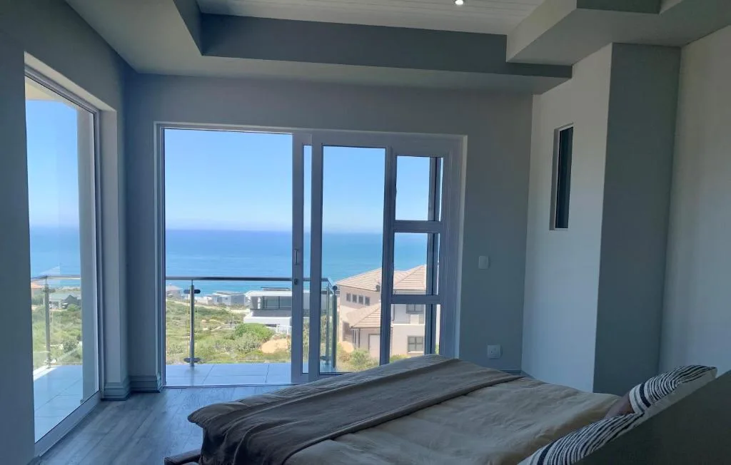 Bedroom with ocean view through large glass doors and windows