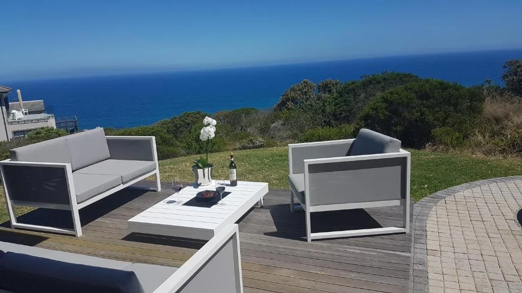 Oceanview deck with modern seating, fire table, and panoramic blue sea horizon