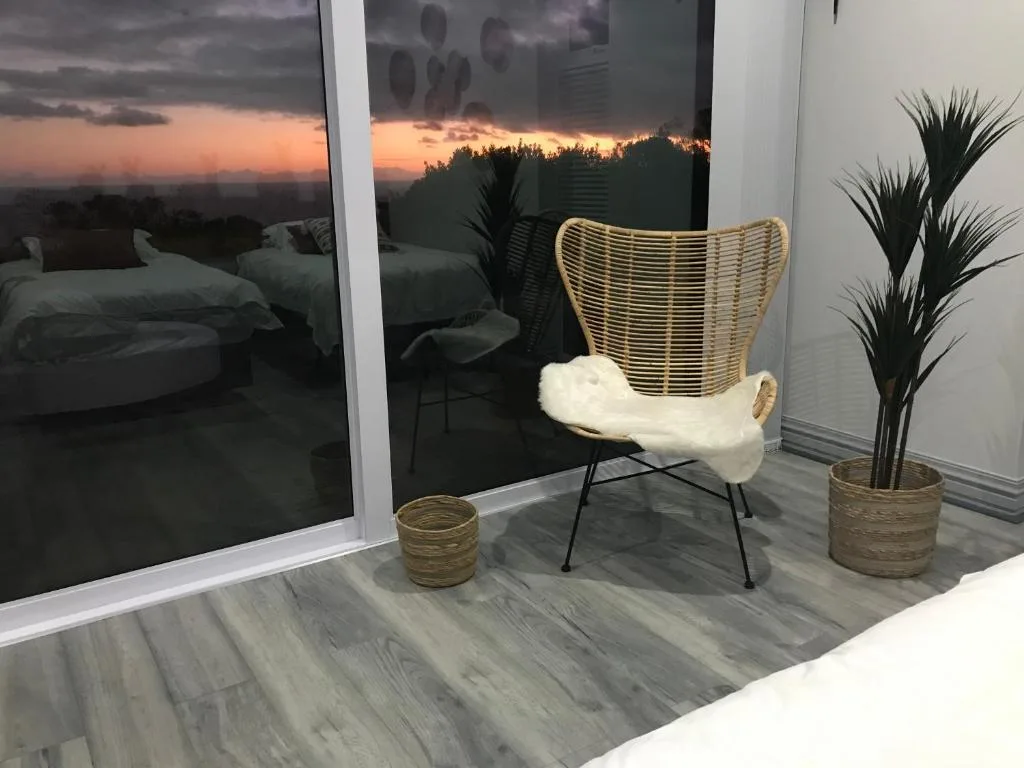 Woven chair on balcony overlooking sunset and forested landscape