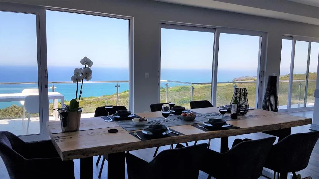 Dining table with ocean and coastal views through large windows