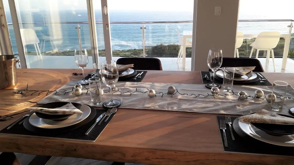 Elegant dining table set with ocean views through floor-to-ceiling windows